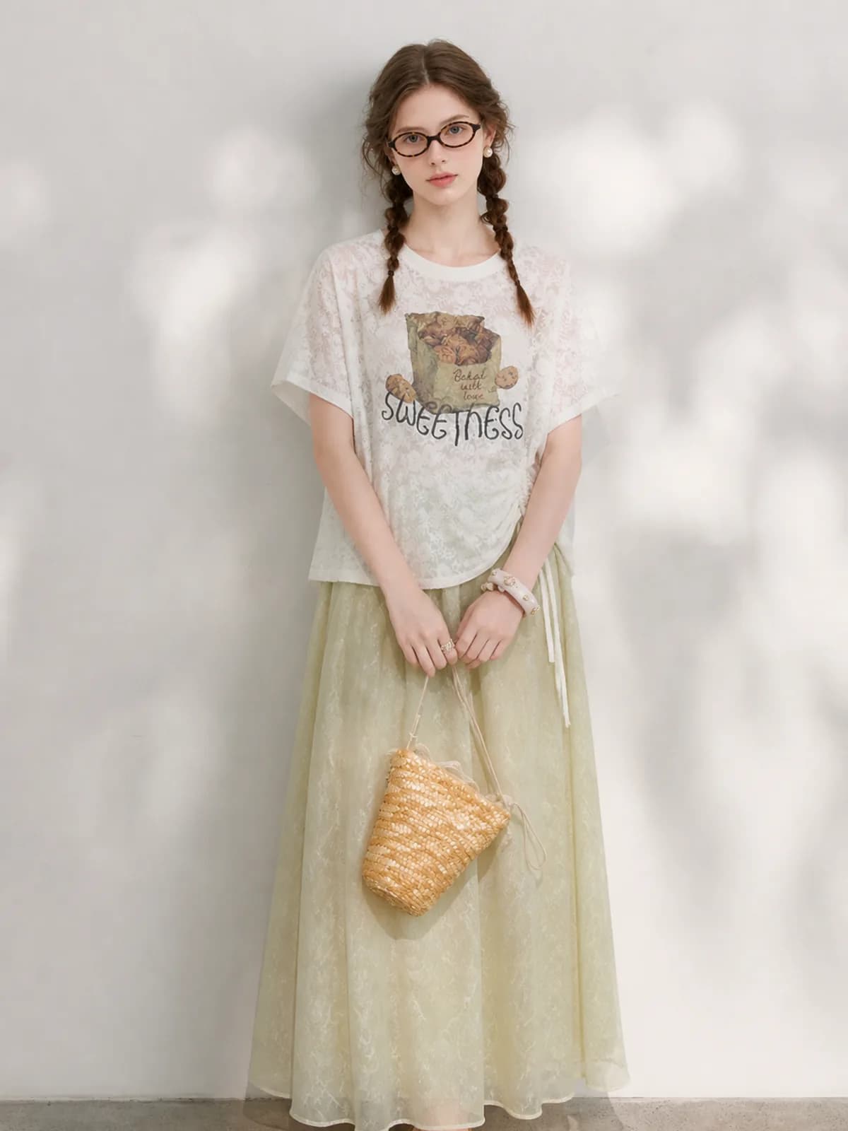 AI model in an ivory graphic lace tee and pale green organza skirt