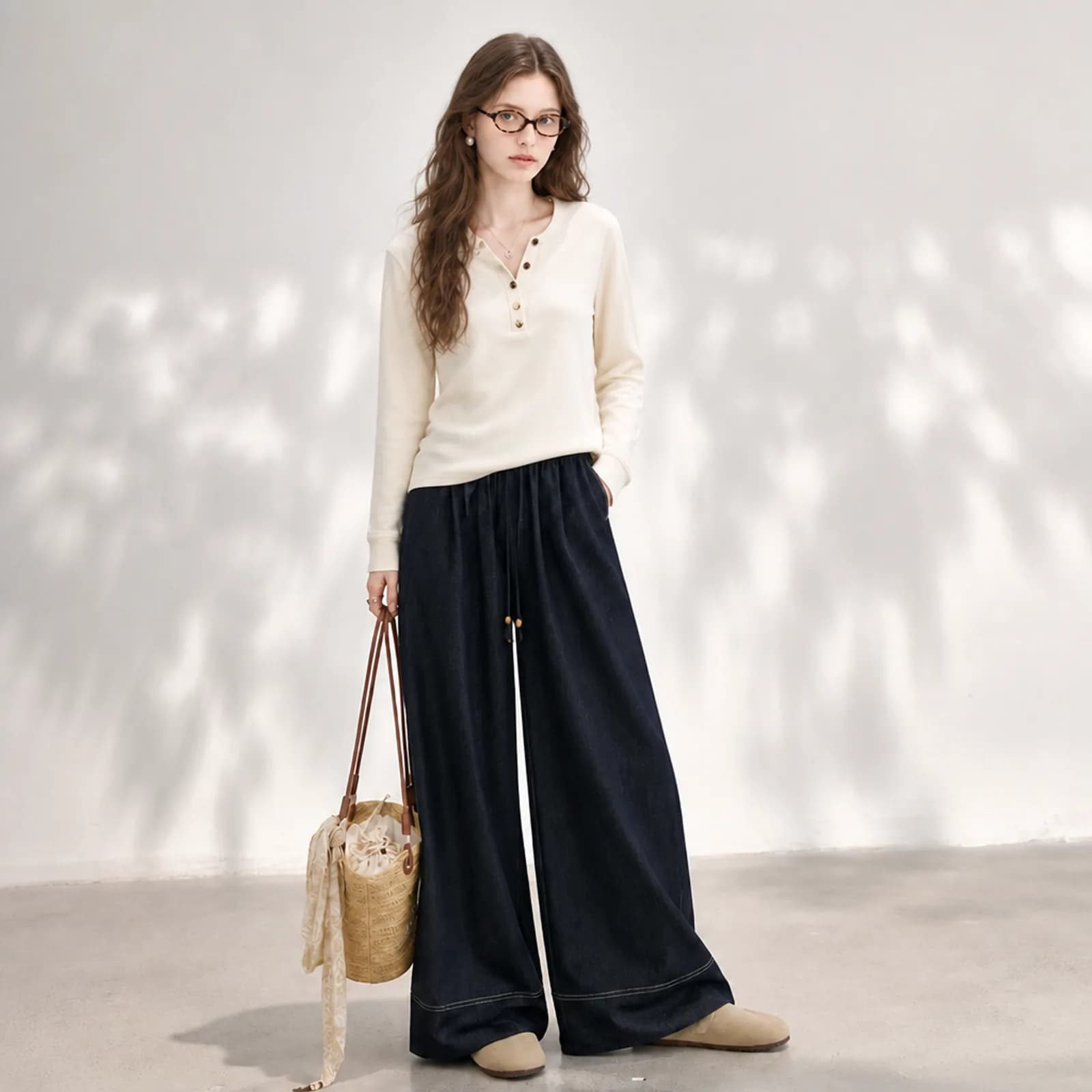 AI model in a cream henley top and dark indigo wide-leg trousers