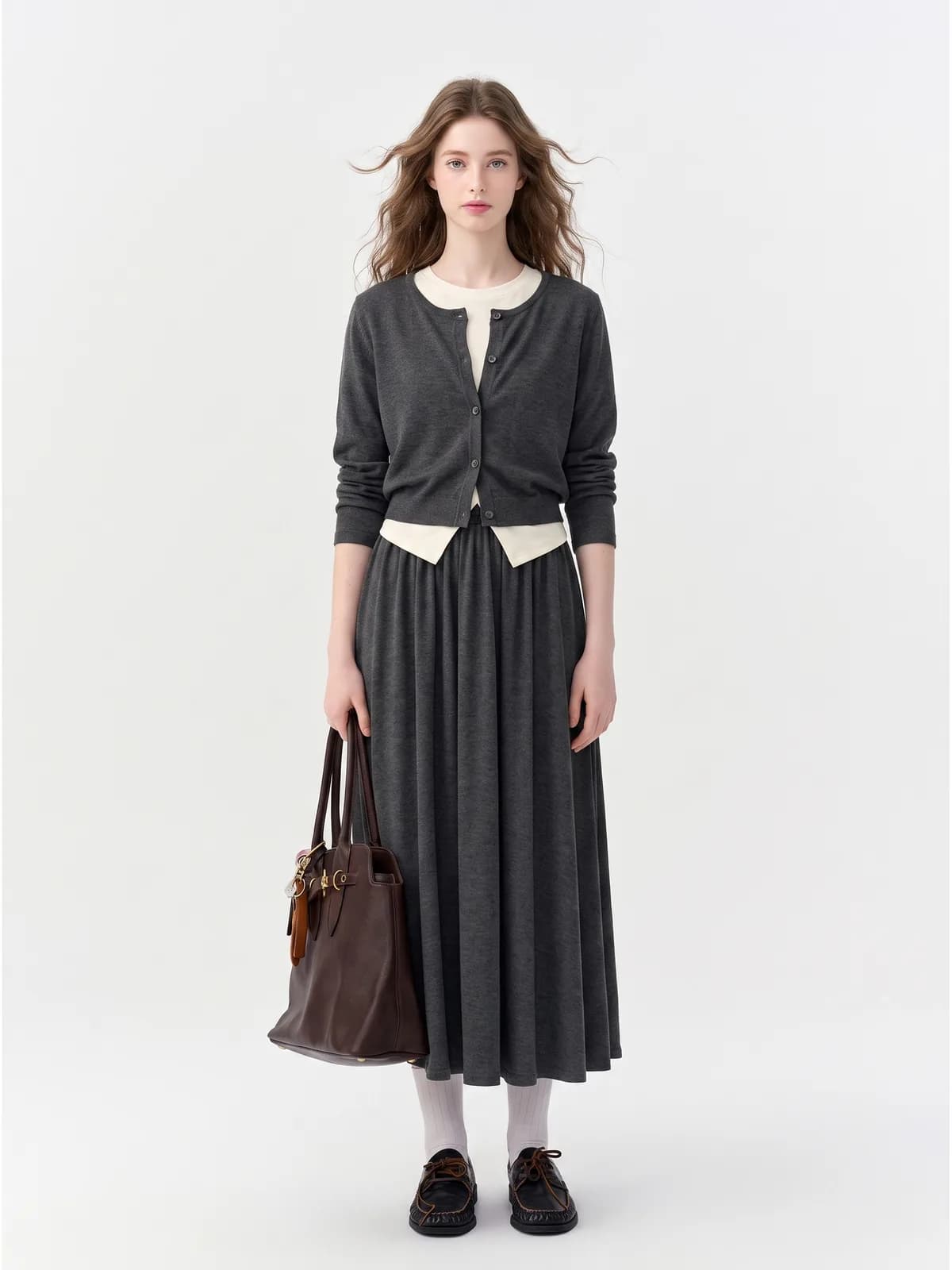 AI model in a charcoal cardigan and matching pleated midi skirt