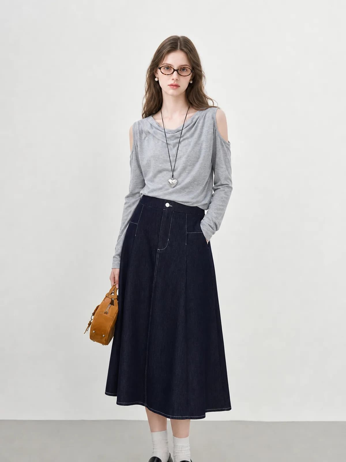 AI model in a grey cold-shoulder top and indigo A-line denim skirt