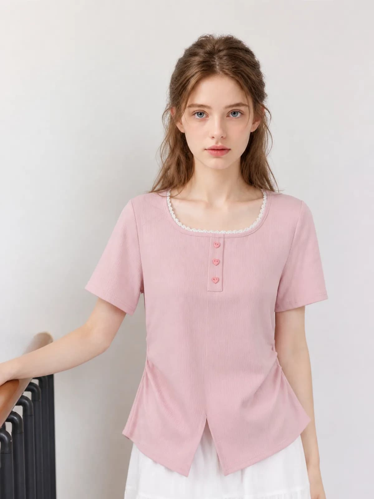 Close crop of a pink ribbed top with white lace trim and heart buttons
