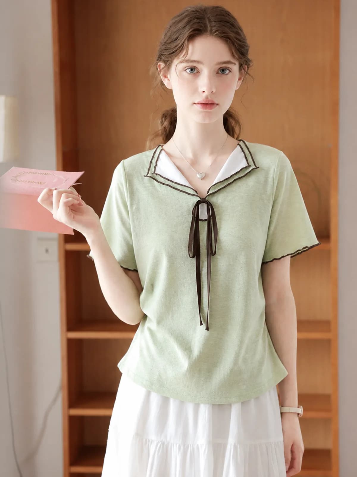 AI model wearing a sage green sailor-collar top with a brown ribbon tie