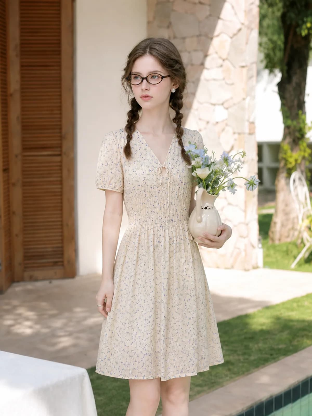 The same cream floral dress photographed on a poolside patio
