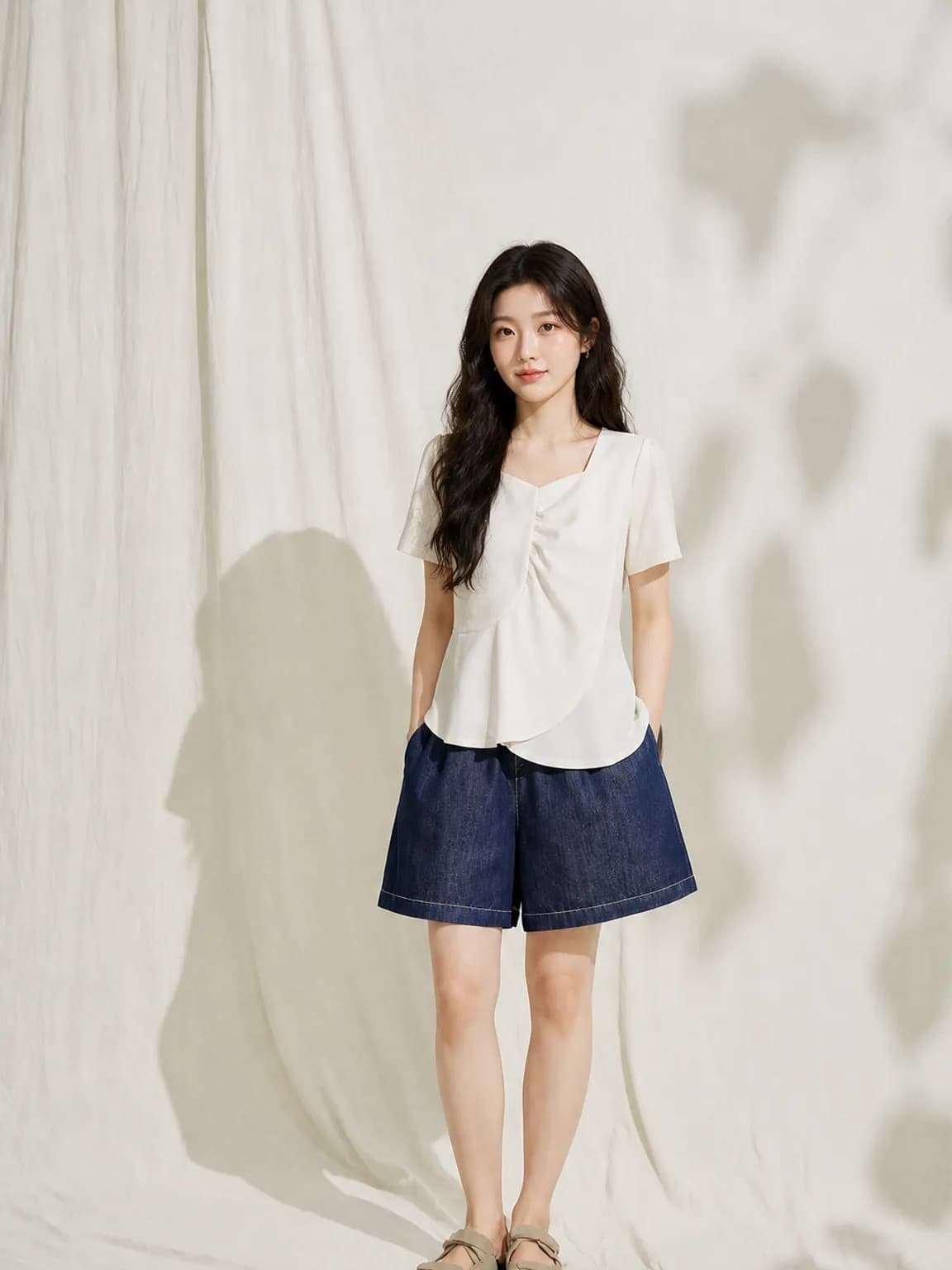 Full-length frame of the ivory gathered-front top with denim shorts