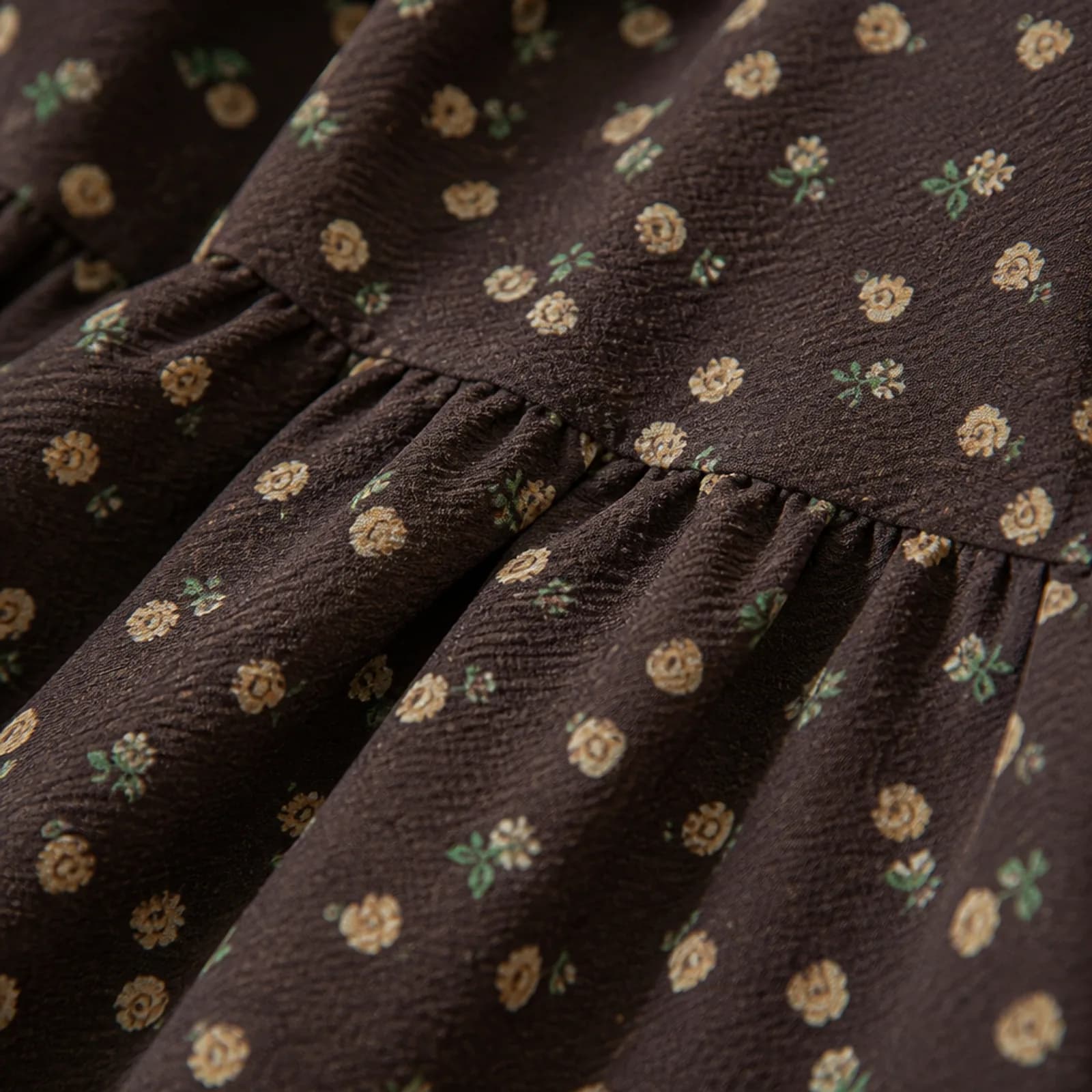 Close-up of brown crinkle fabric with a small cream rose print and green sprigs