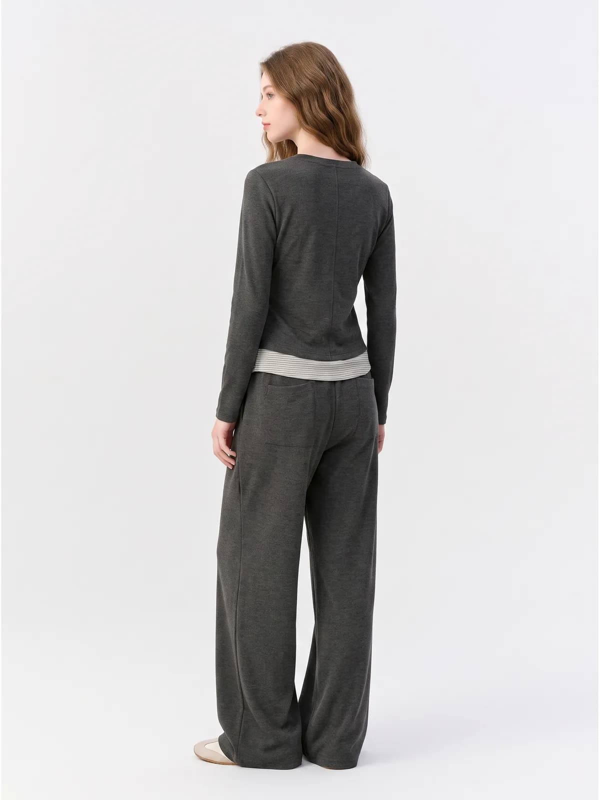 Back view of a charcoal two-piece knit set with a striped waistband on an AI model