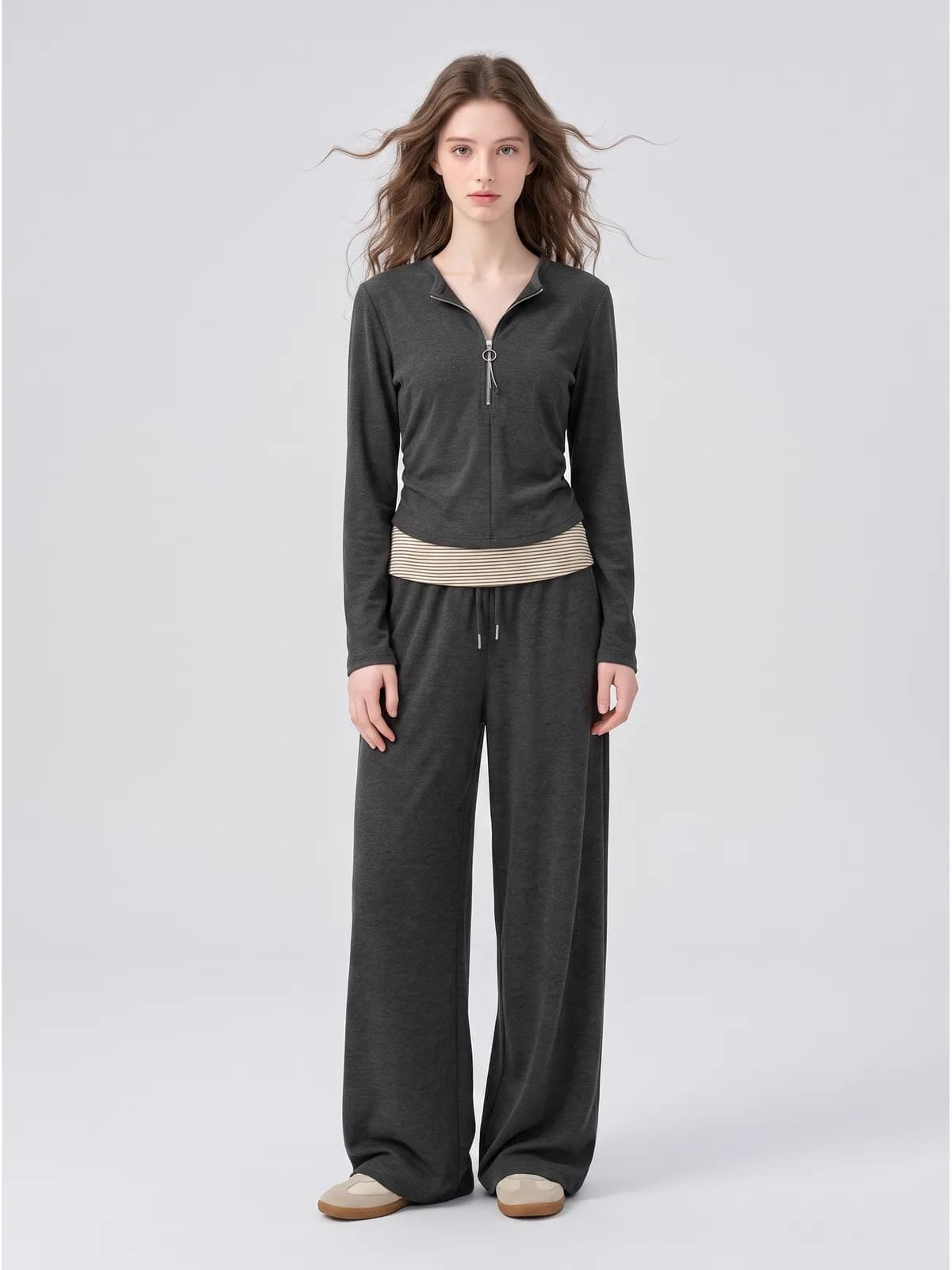 AI model wearing a charcoal two-piece knit set with a striped contrast waistband, front view