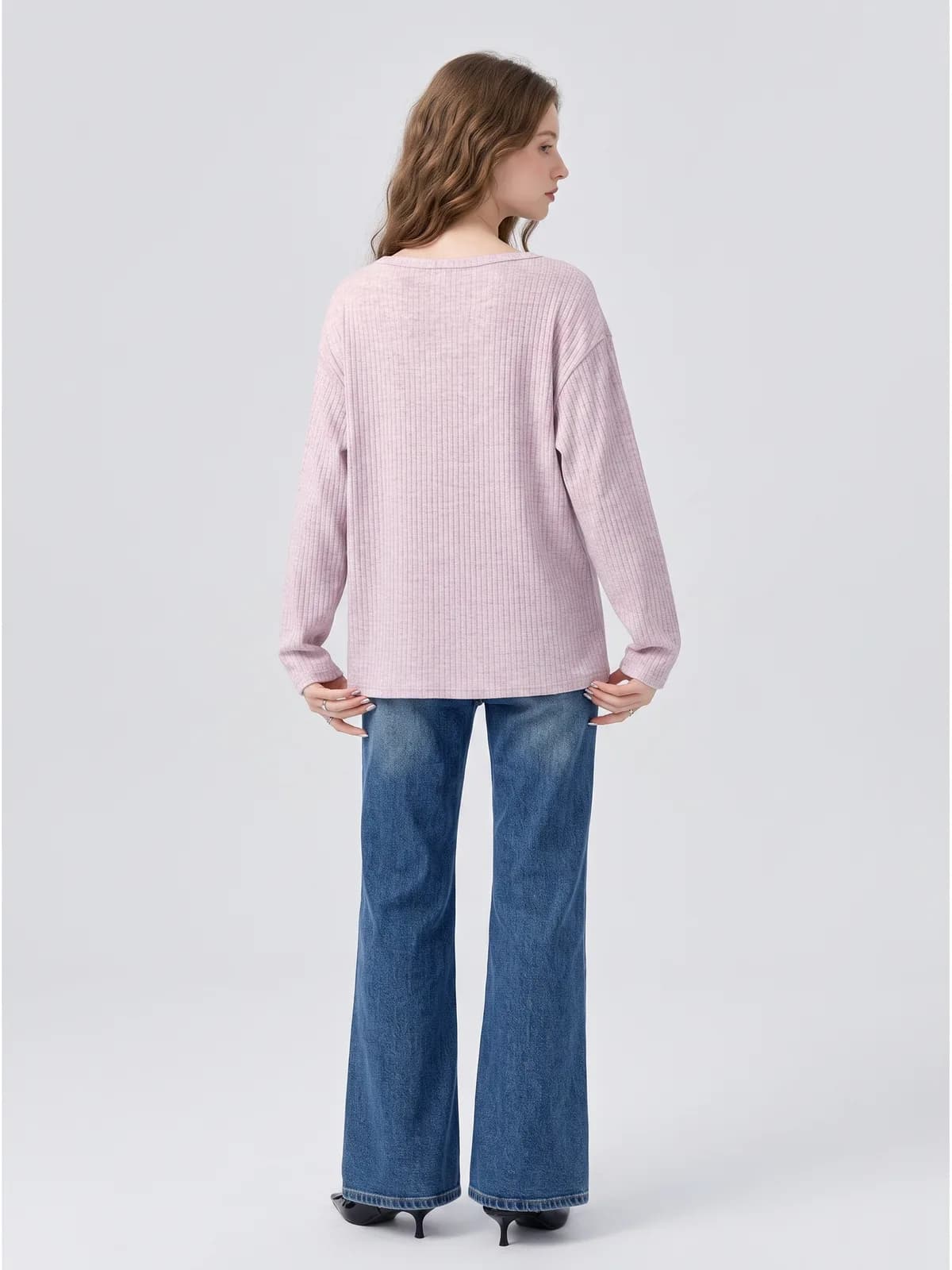 Back view of a pink ribbed cardigan with wide-leg jeans on an AI model